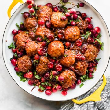slow cooker gluten free meatballs with cranberry sauce on a serving dish topped with extra cranberries