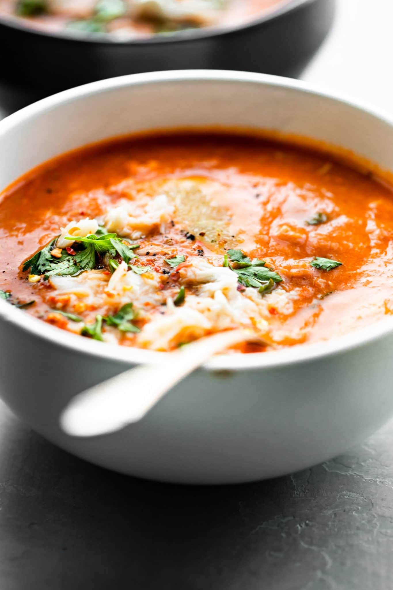 a bowl of tomato crab bisque with a spoon in it