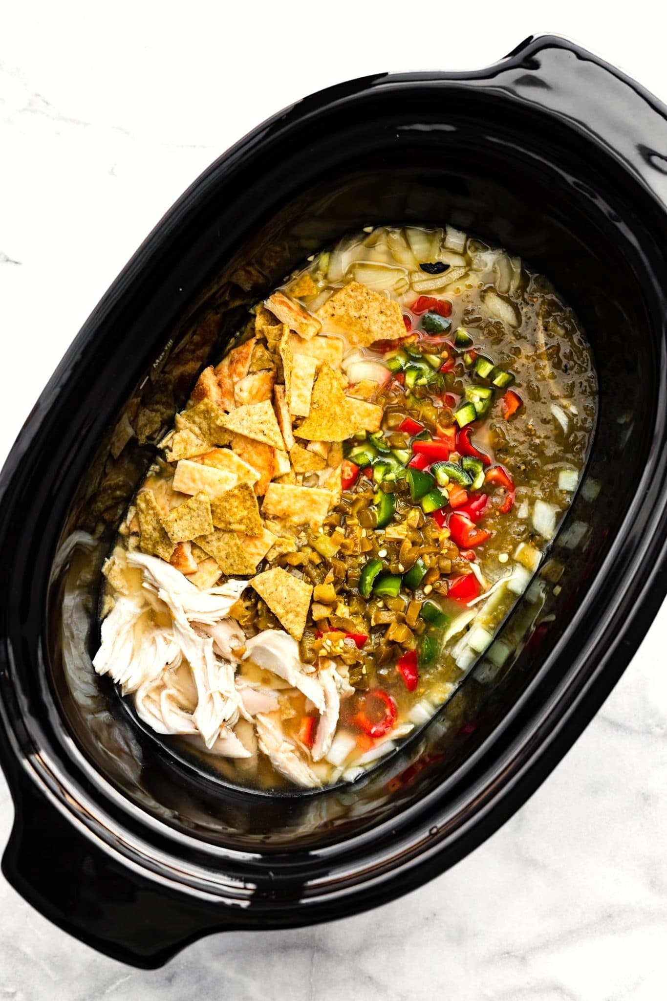 chicken, green chiles, bell peppers, onions, borth, and tortilla chips in a slow cooker for chicken chili verde