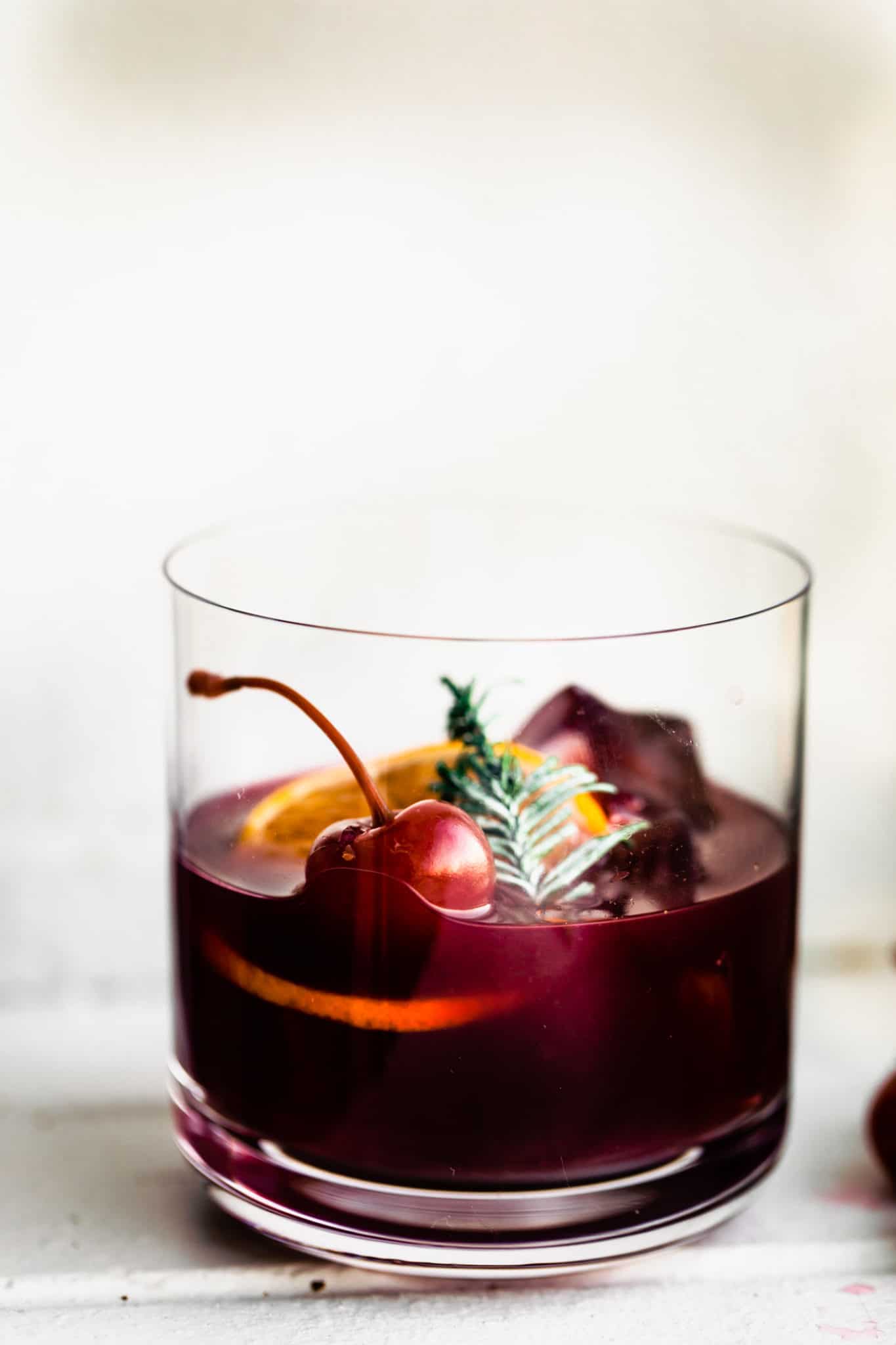 yuletide moon red wine cocktail topped iwth ice, an orange slice, and a cherry