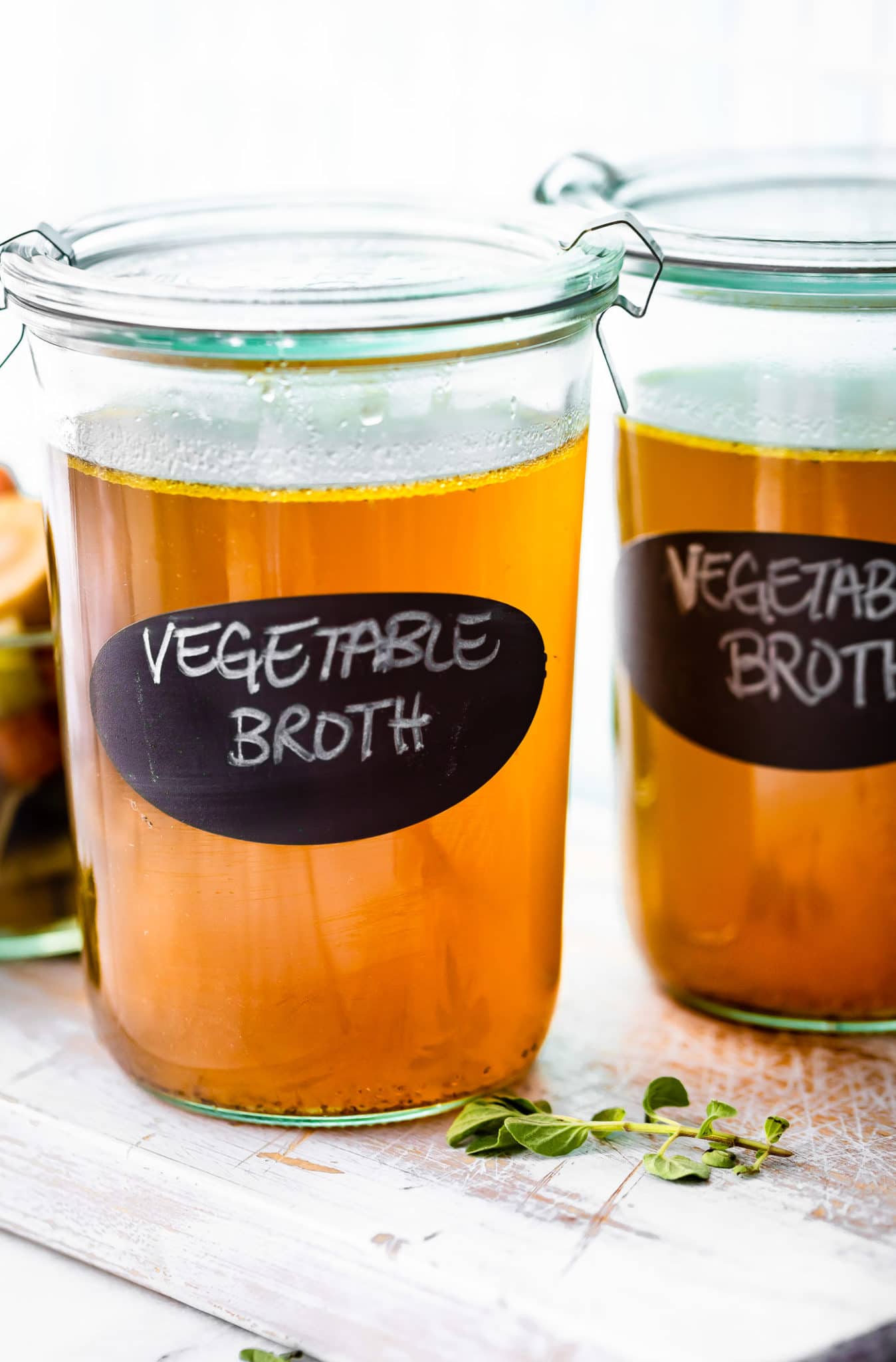 glass jars of homemade vegetable broth with "vegetable broth" written in white.