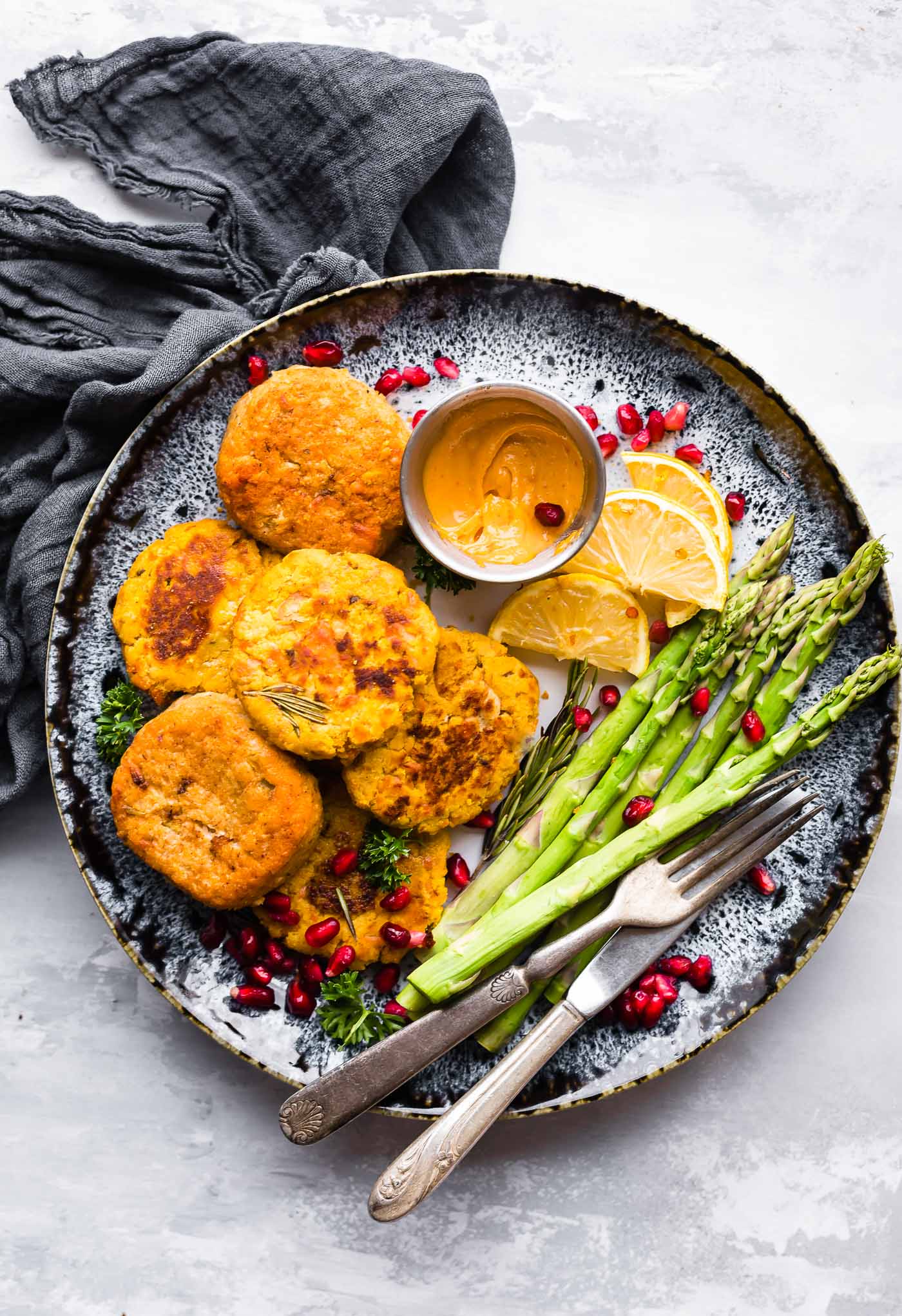 salmon cakes on a plate with asparagus and a dipping sauce
