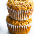 two healthy carrot cake muffins in muffin liners stacked on top of each other
