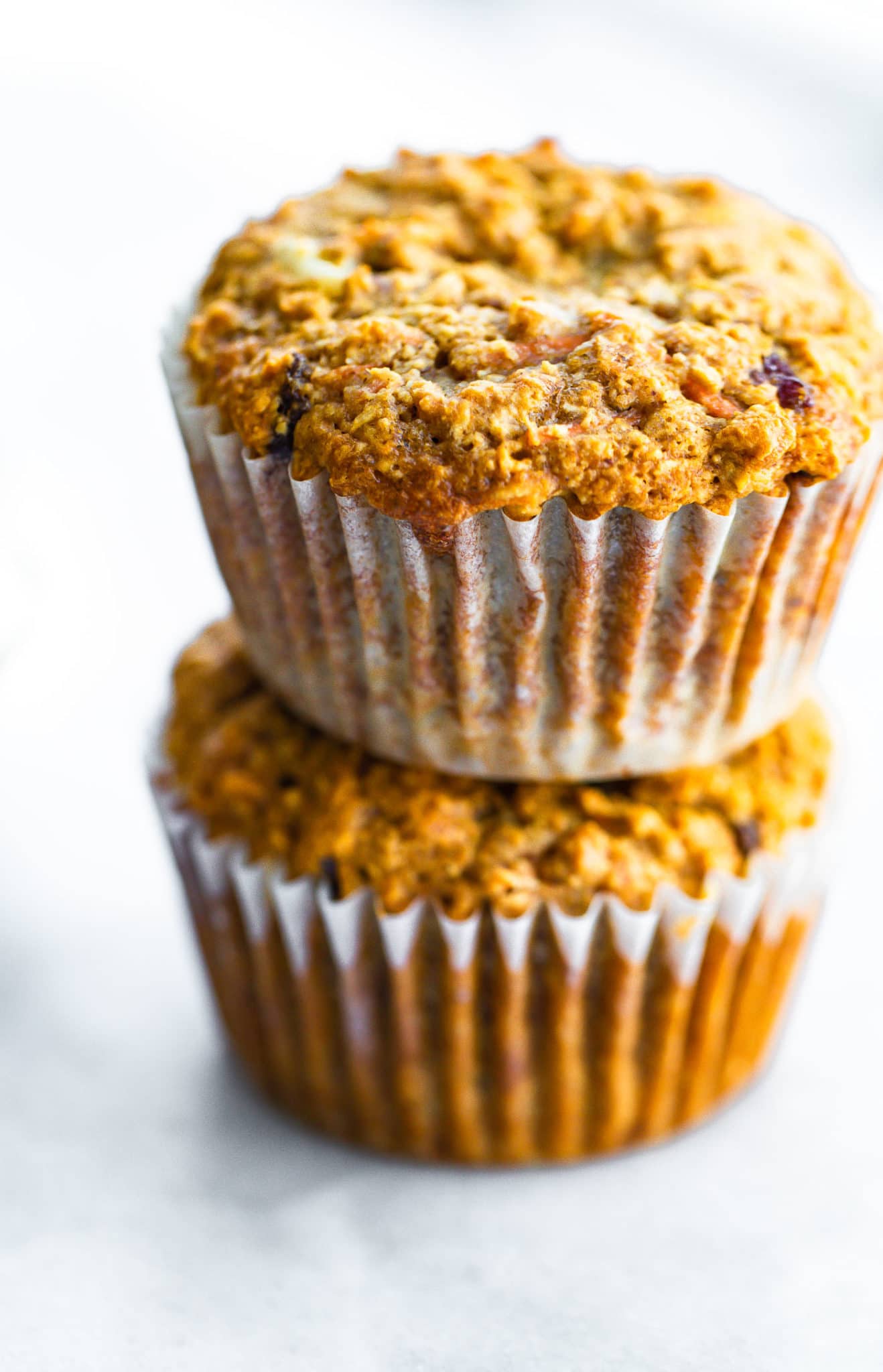 two healthy carrot cake muffins in liners stacked on top of each other