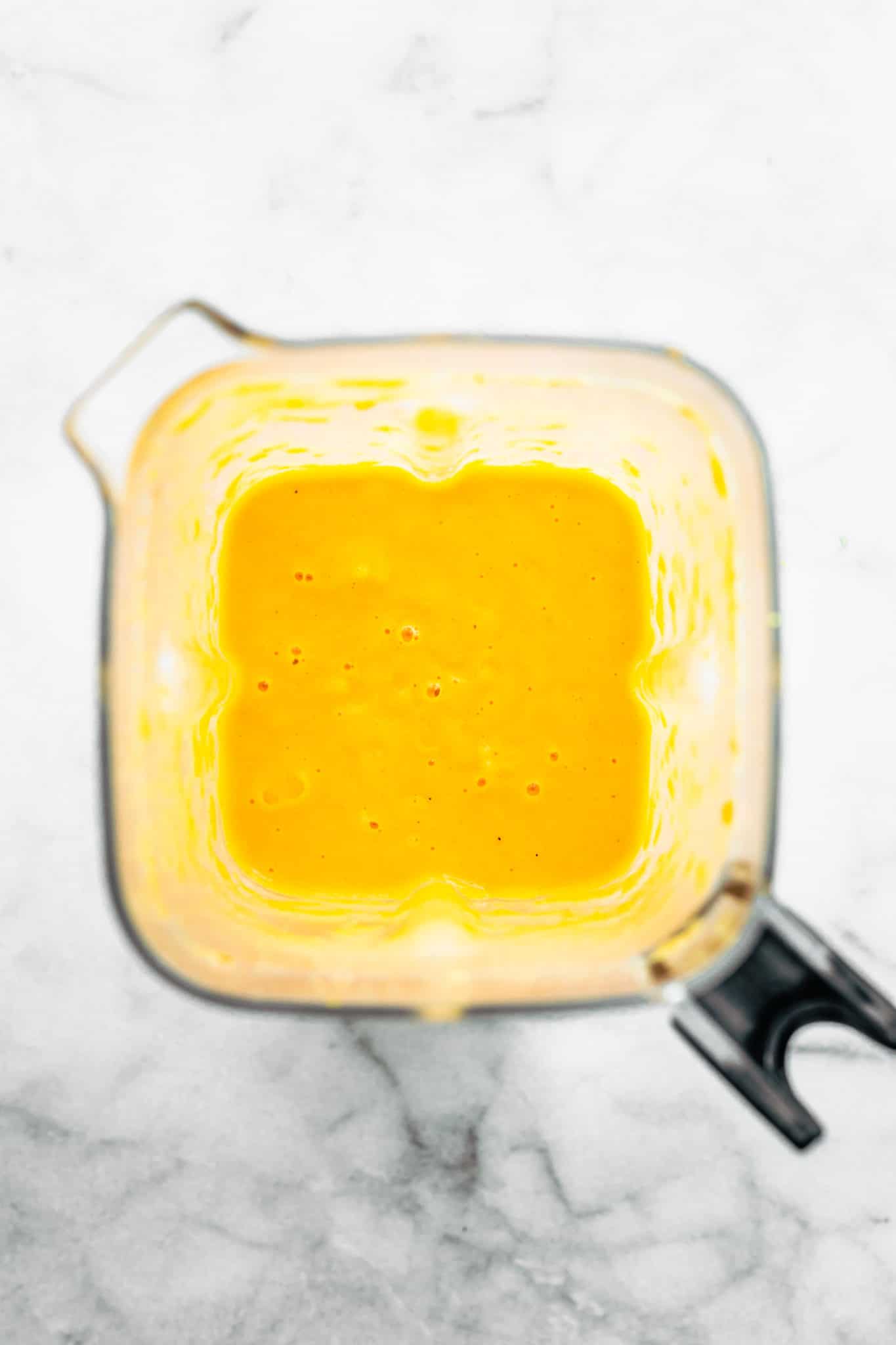 overhead image of vegan cheese sauce in a blender for vegan broccoli cheese soup