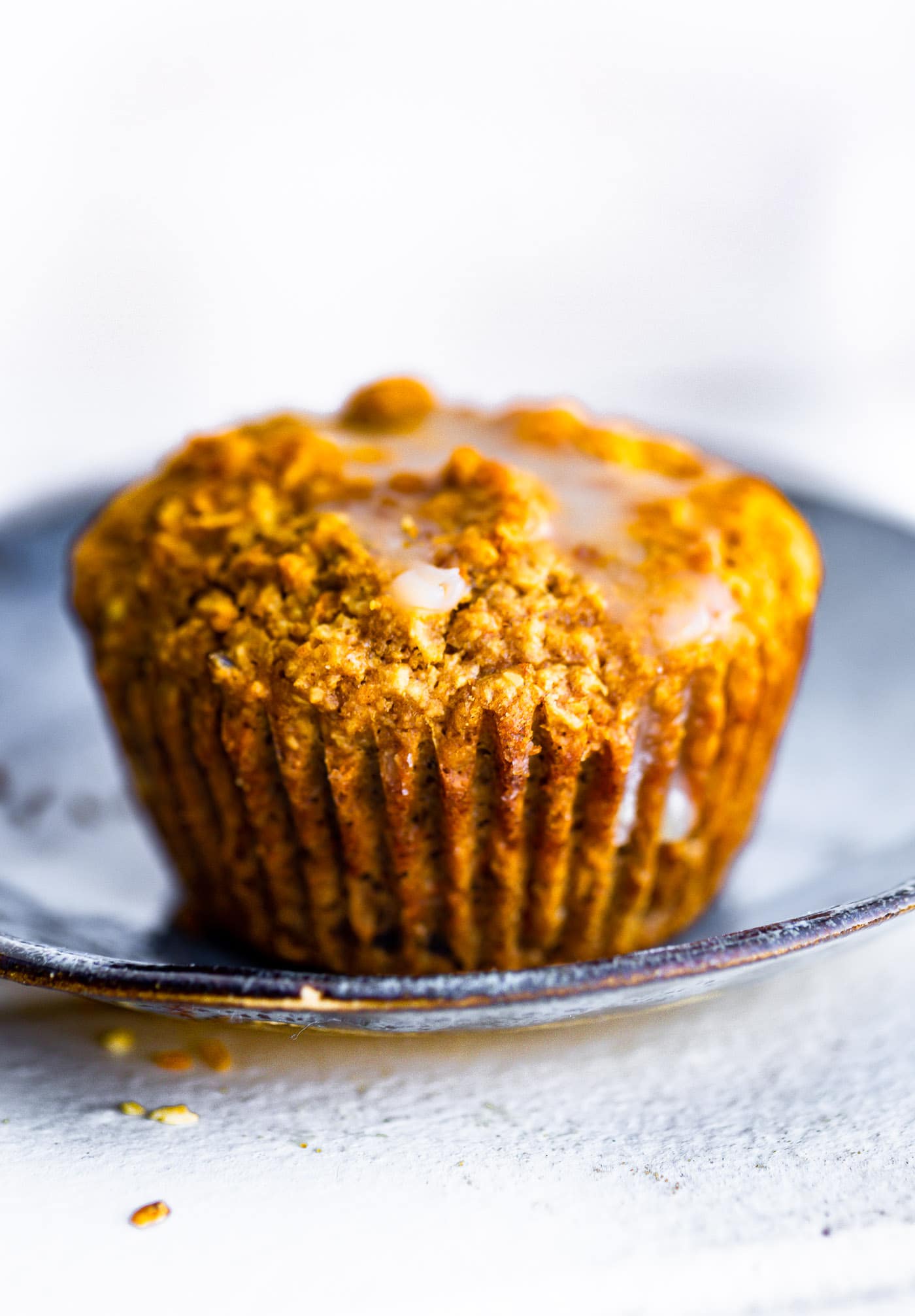 a glazed healthy carrot cake muffin on a blue plate