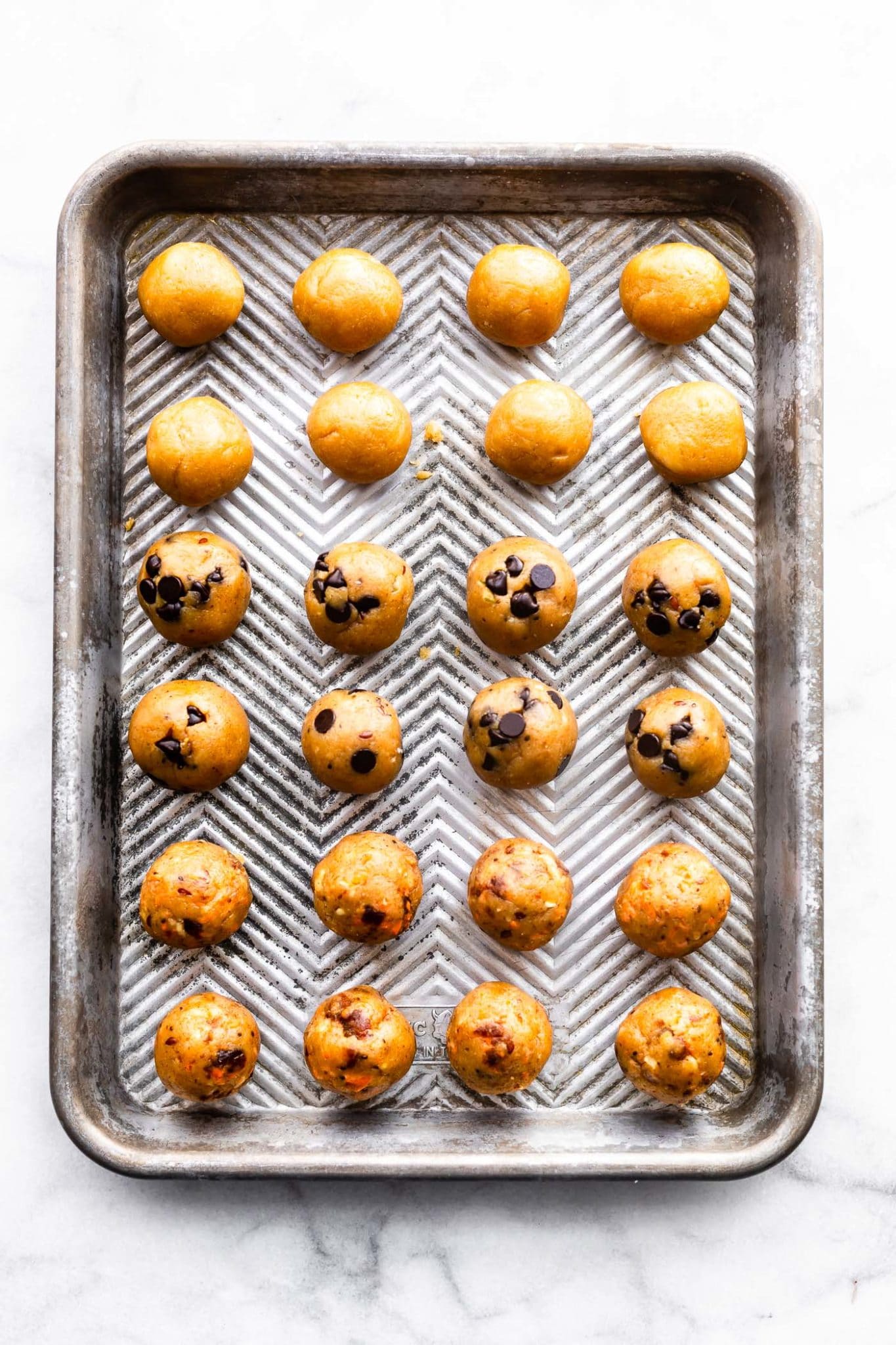 chocolate chip, carrot cake, and vanilla cake balls on a baking sheet before being coated with chocolate