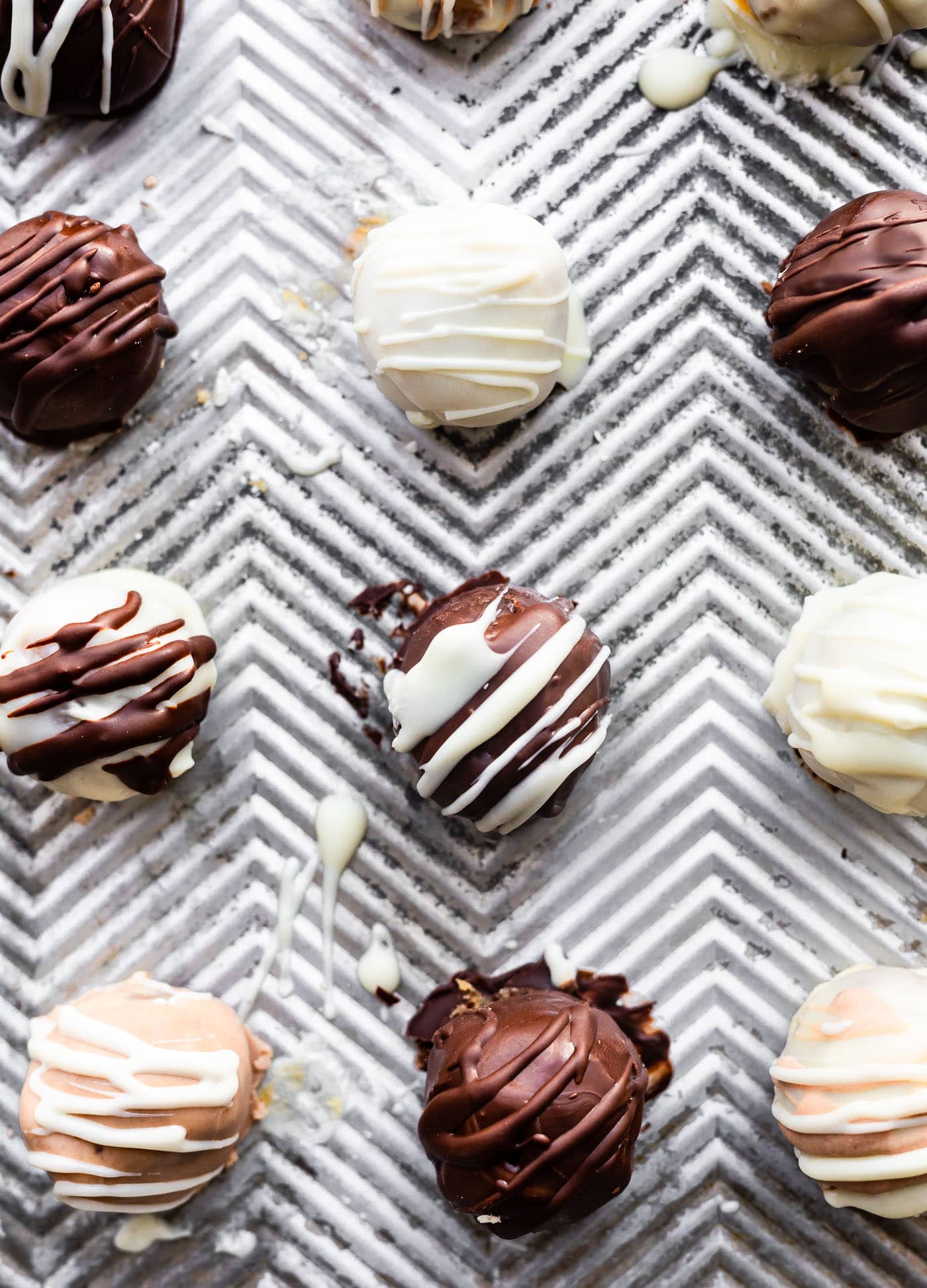 3 cake ball flavors coated in white and dark chocolate sitting on a caking sheet to set