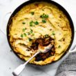 a spoon in a pan full of potato and cauliflower shepherd's pie