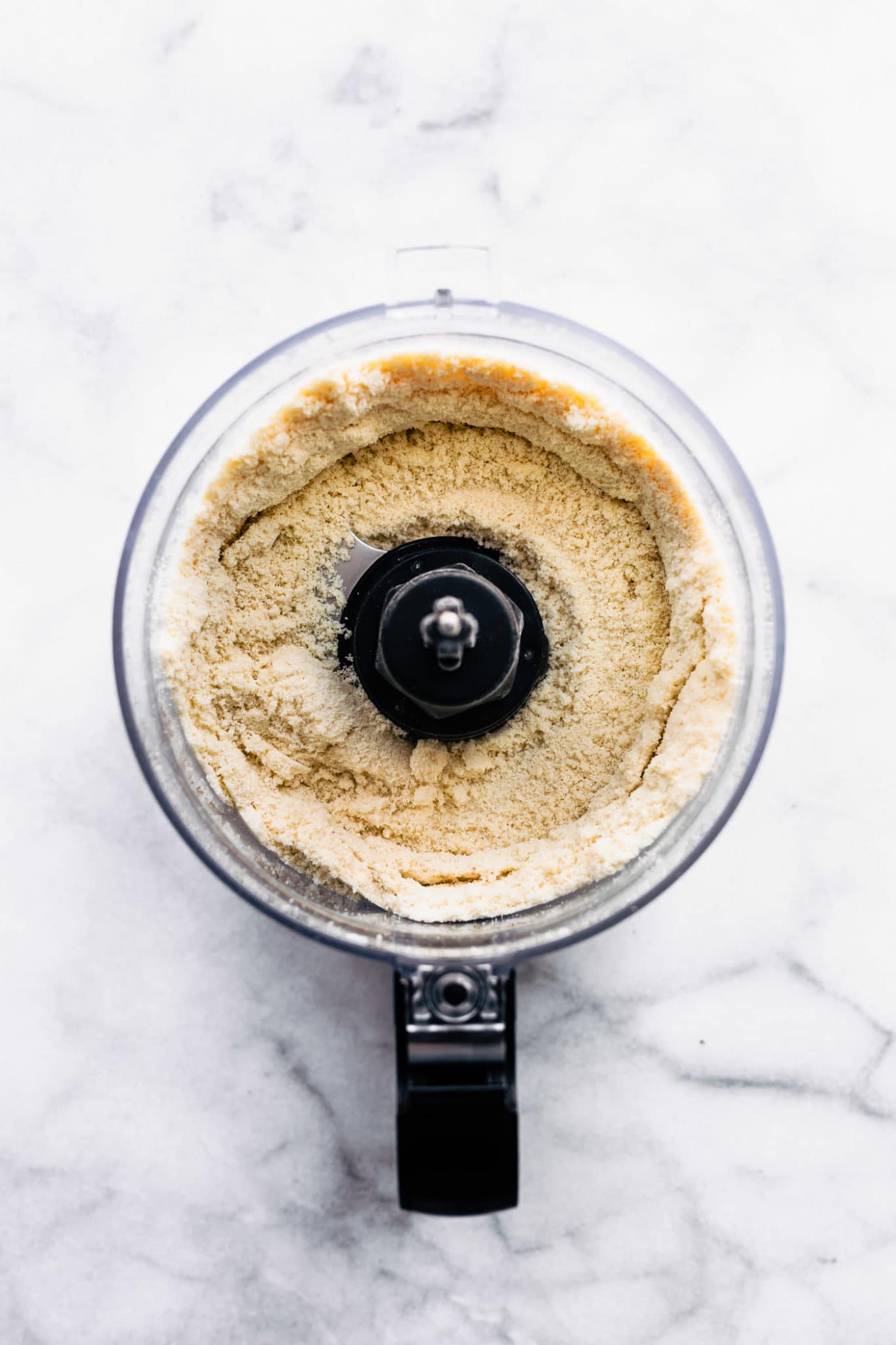 an overhead image with vegan vanilla cake batter ingredients in a food processor
