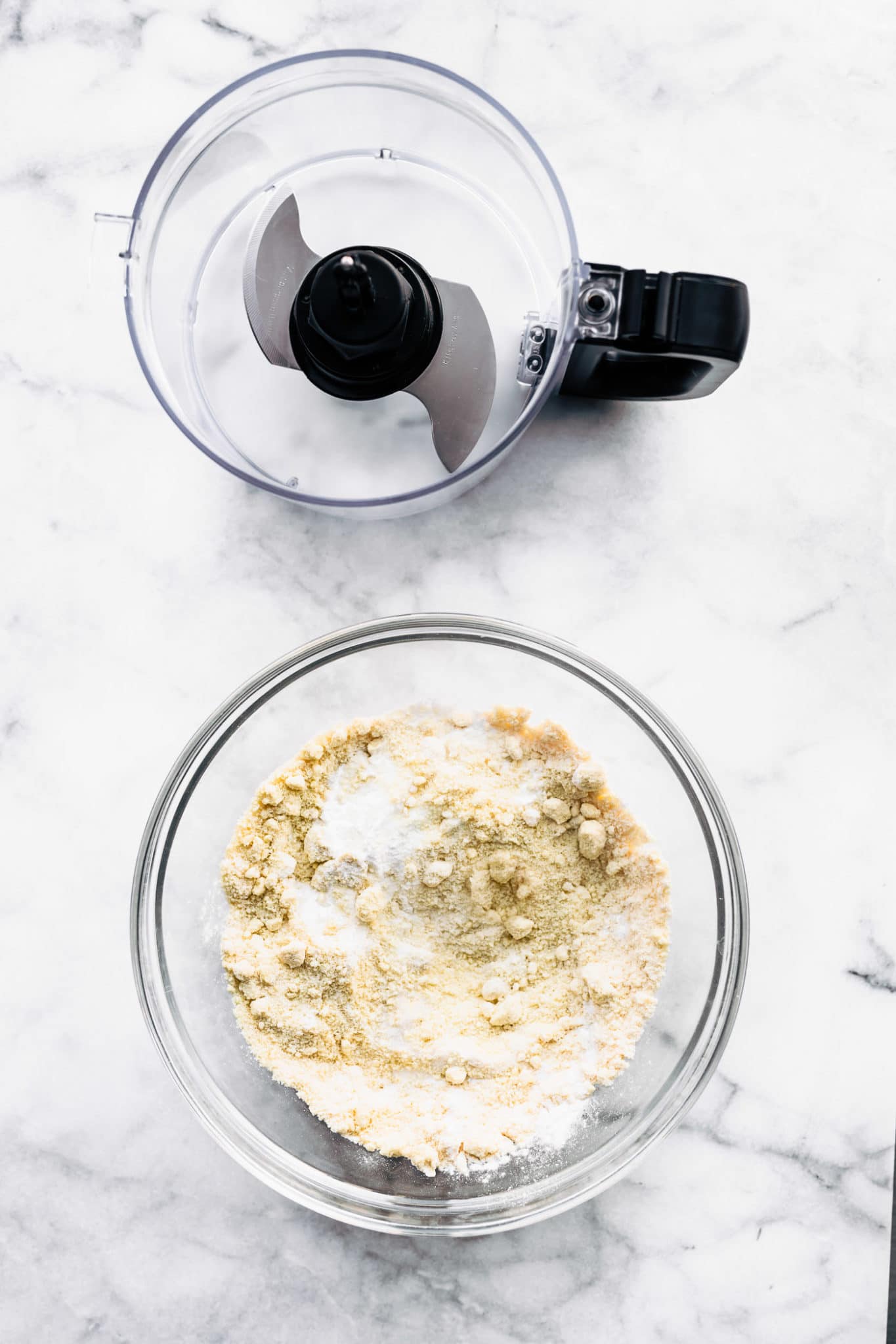 overhead image of a food processor and a glass bowl with coconut flour for vegean vanilla cake with frosting
