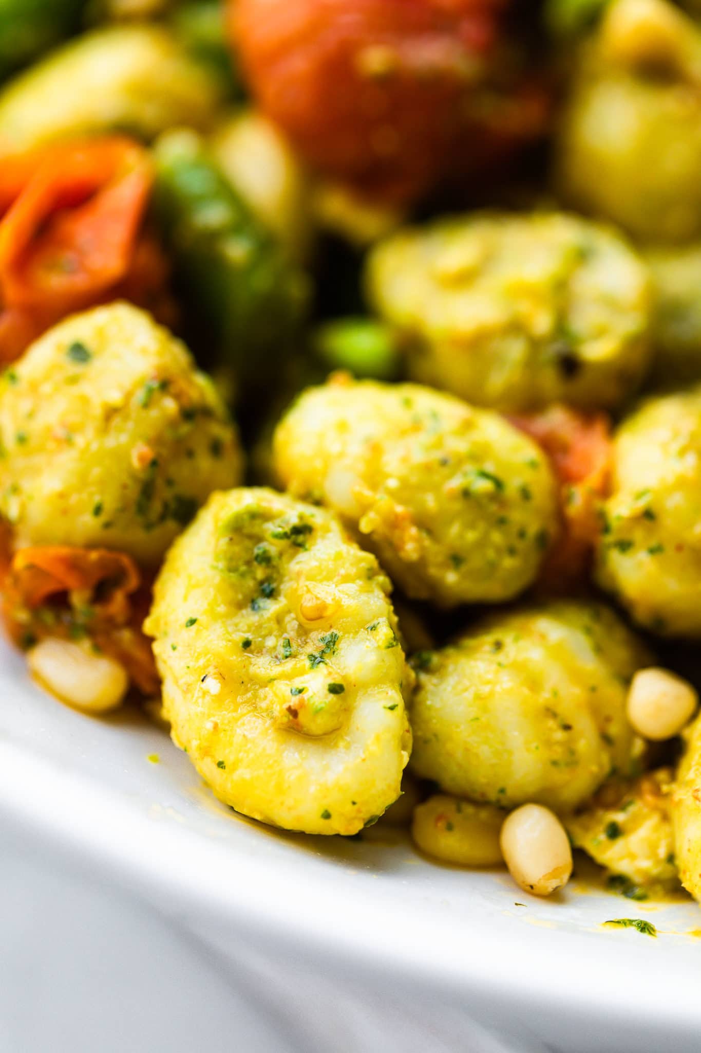 close up image of gluten free gnocchi coated with pesto in a pasta salad