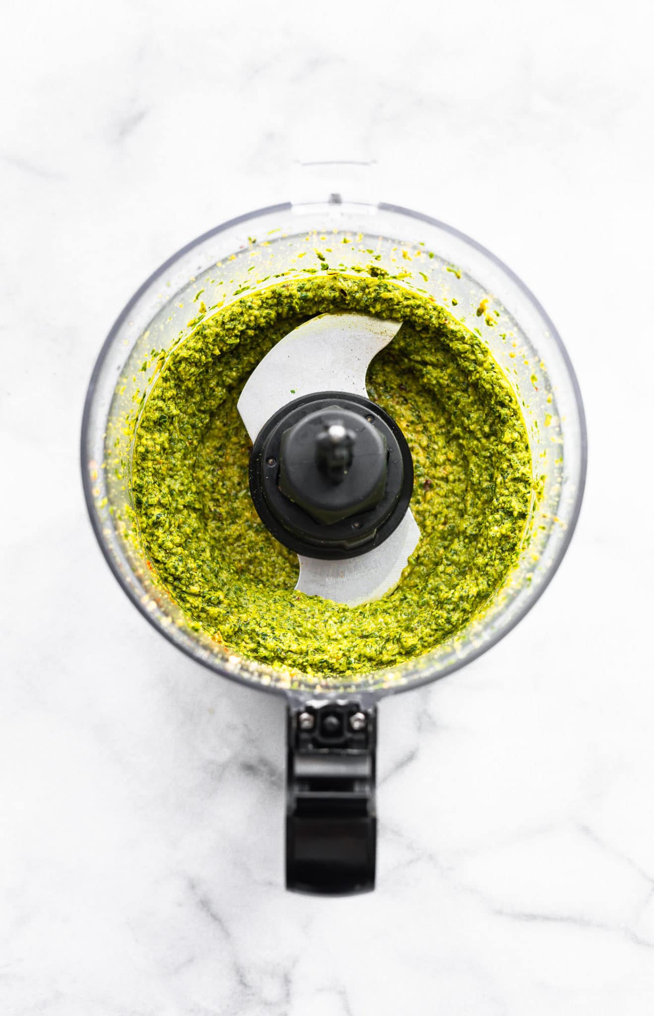 an overhead image of blended cilantro pesto sauce in a food processor