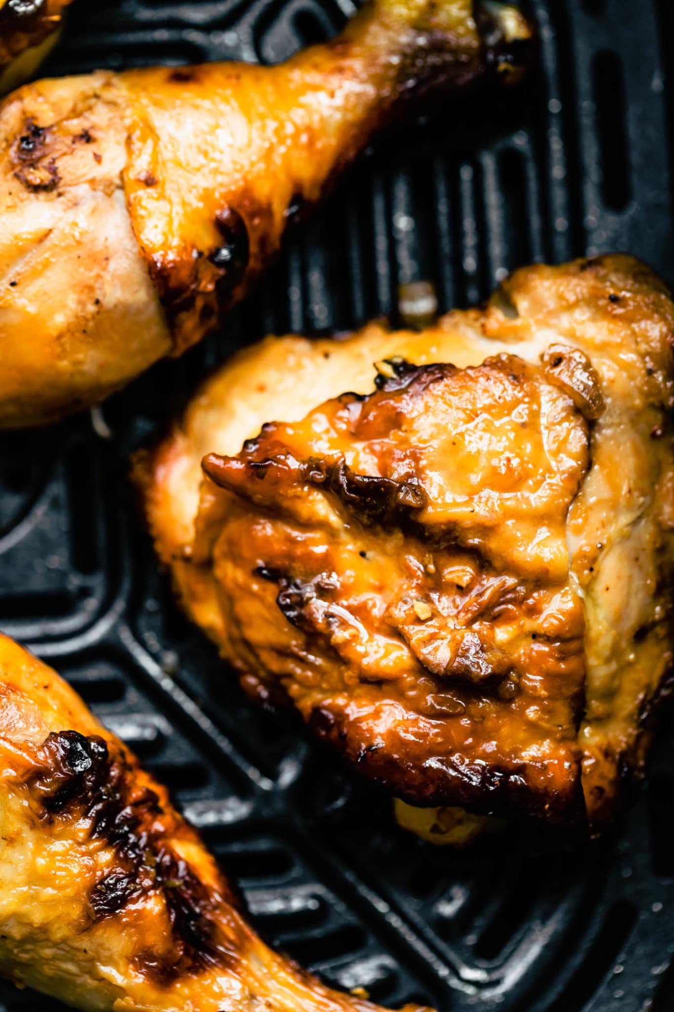 a close up image of honey ginger air fryer chicken thighs in an air fryer basket