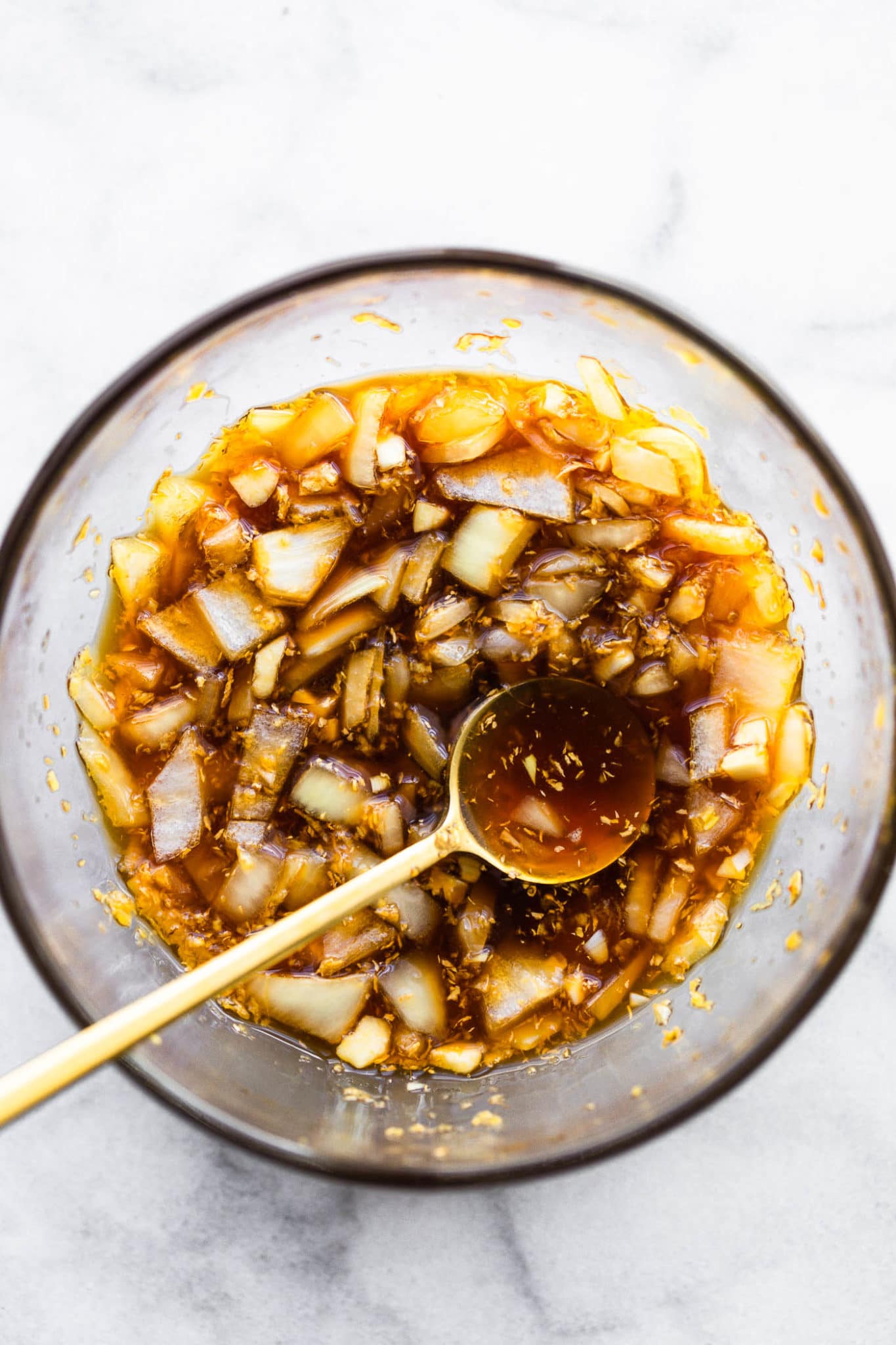 a glass bowl filled with honey ginger sauce for air fryer chicken with a golden spoon dipped into the sauce