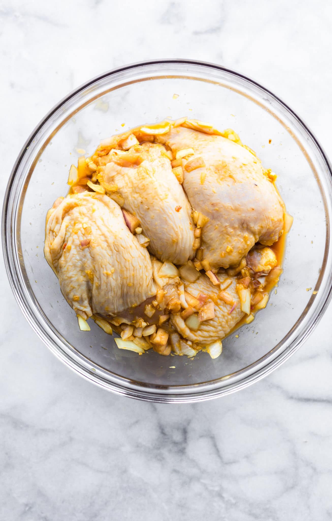 raw chicken marinating in honey ginger sauce in a glass bowl for air fryer chicken