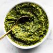 a small white bowl filled with cilantro pesto with a golden spoon dipping into the center