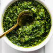 a white bowl filled with mint chimichurri sauce with a golden spoon dipped in the center