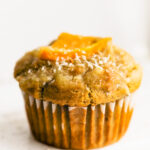 orange oat coconut muffin side shot with white backdrop