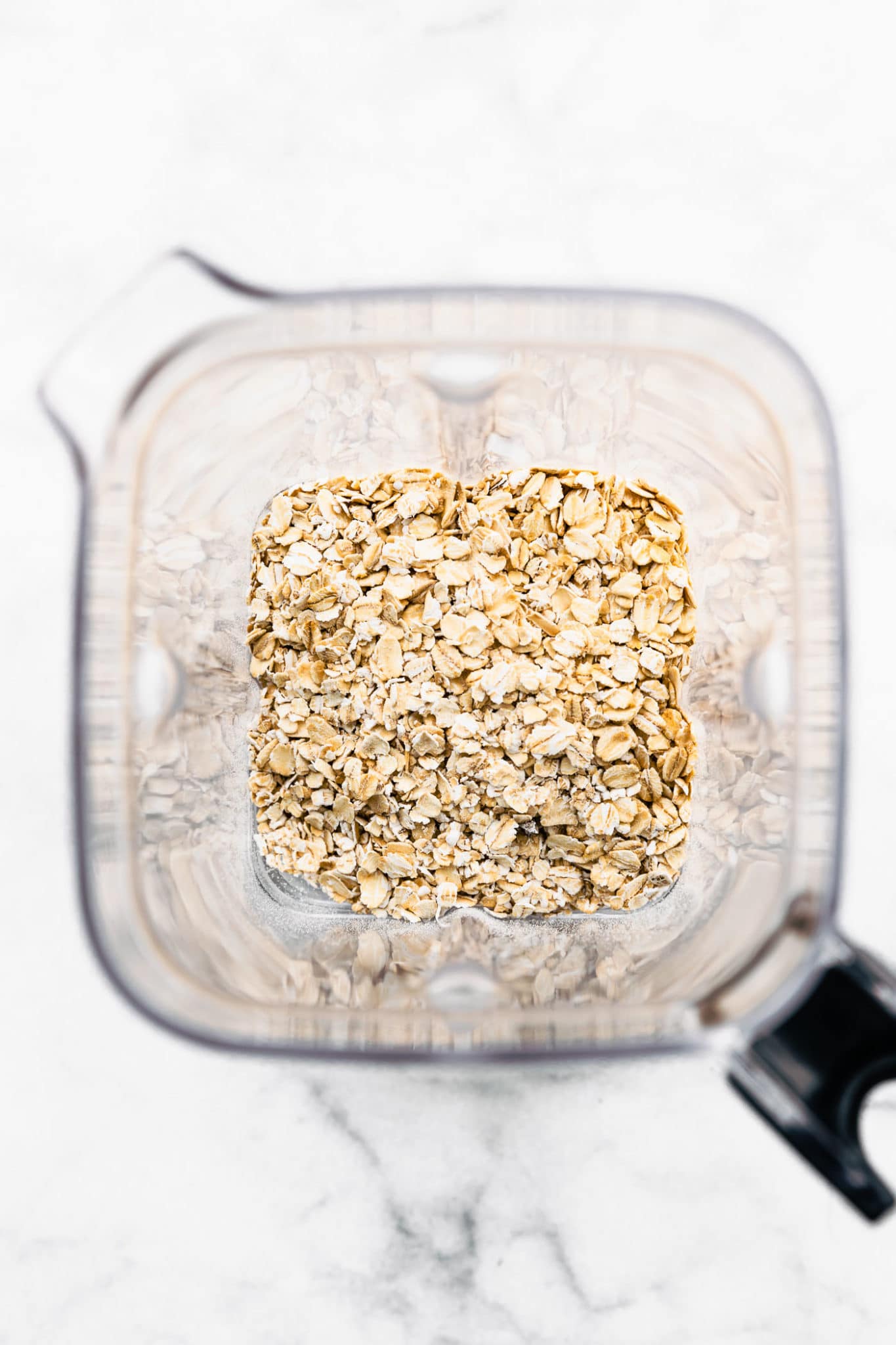 overhead image of whole oats in a blender to make oat flour