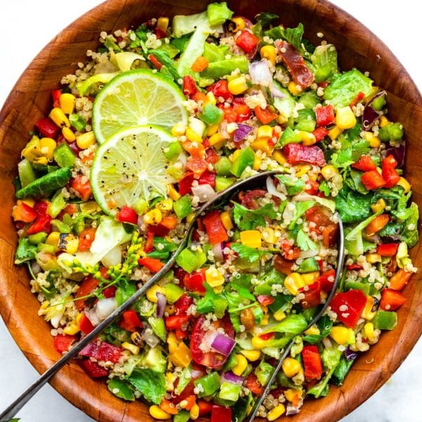 Fiesta quinoa salad in wooden bowl with two lime slices as garnishFiesta quinoa salad in wooden bowl with two lime slices as garnish