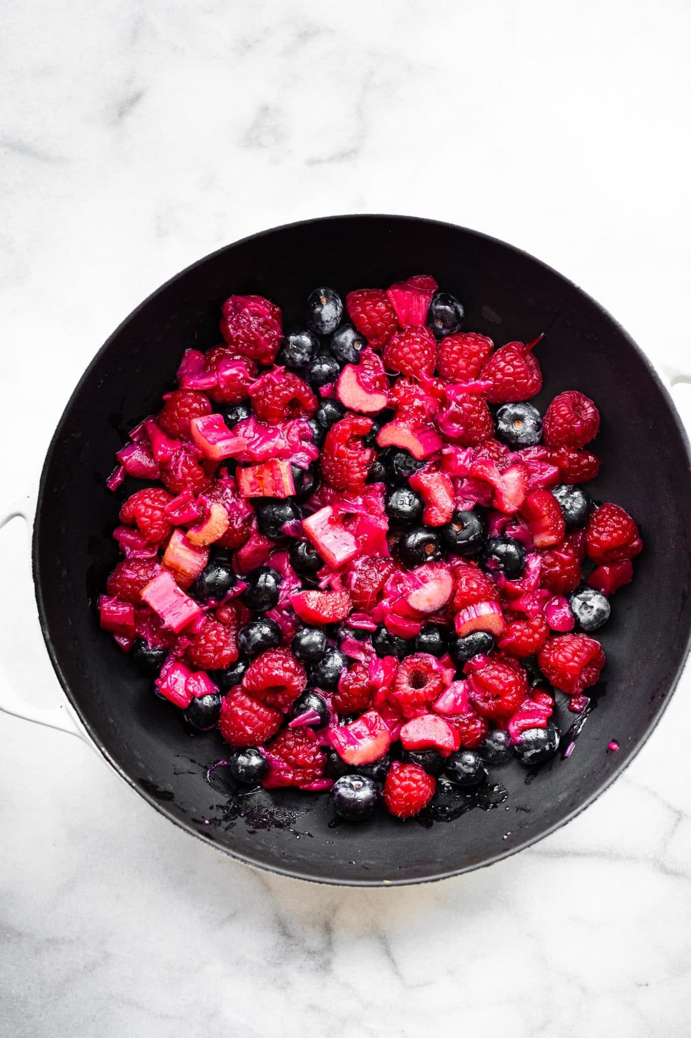 Fresh mixed berries and rhubarb in skillet for a berry rhubarb crumble.