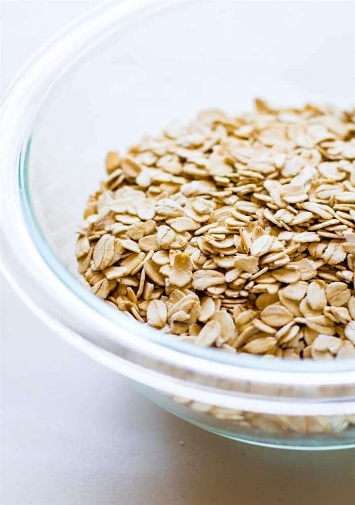 a close up image of a clear glass bowl full of whole rolled oats