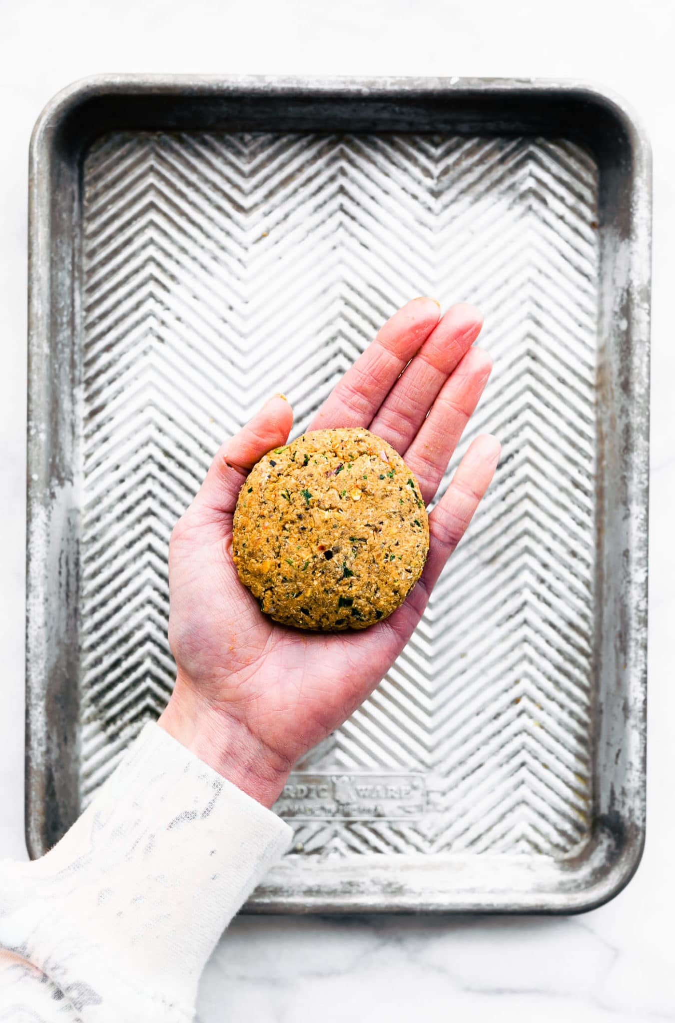 a formed uncooked vegan greek quinoa burger patty in a woman's hand