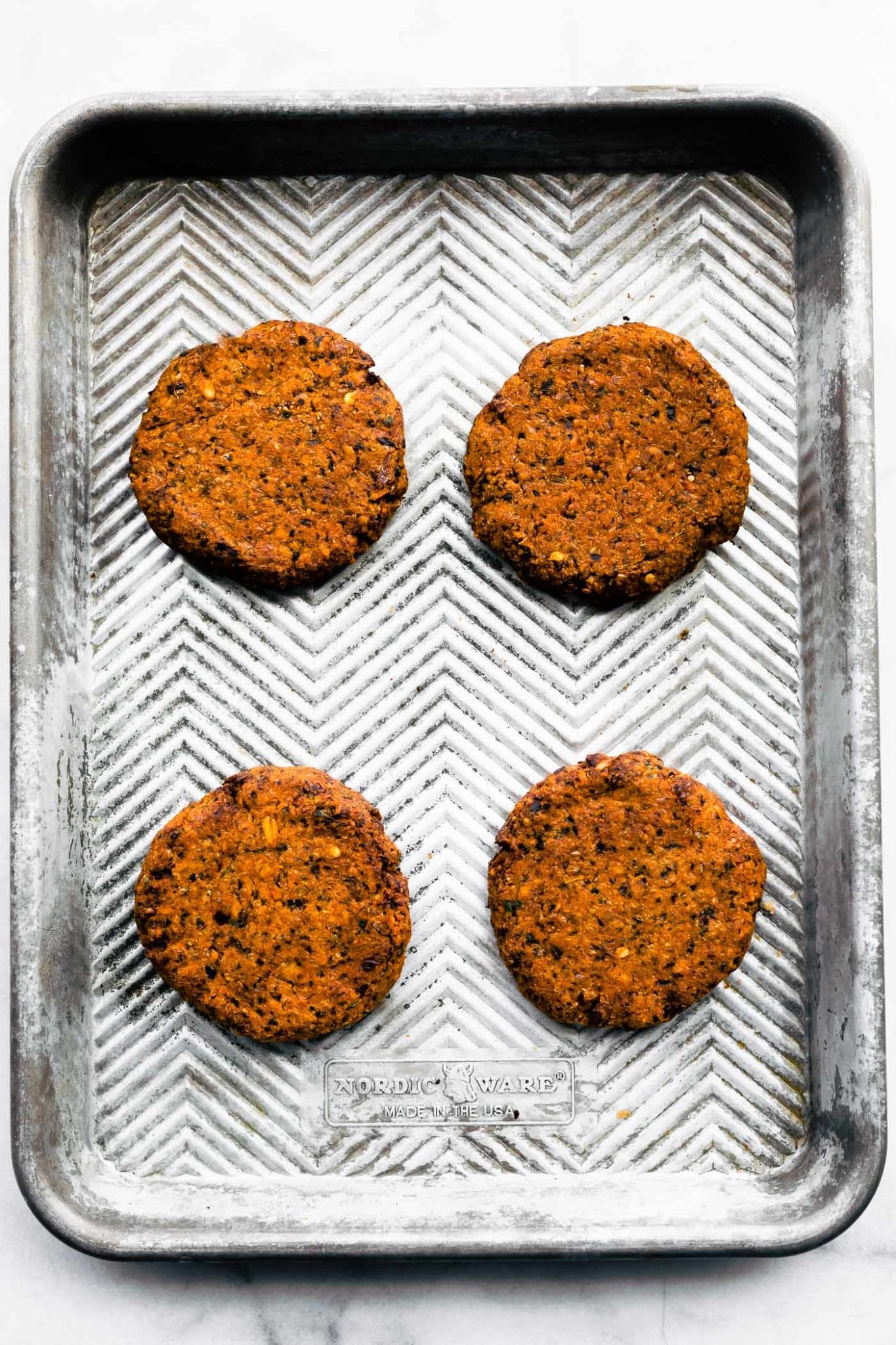 four vegan greek quinoa burger patties on a baking sheet