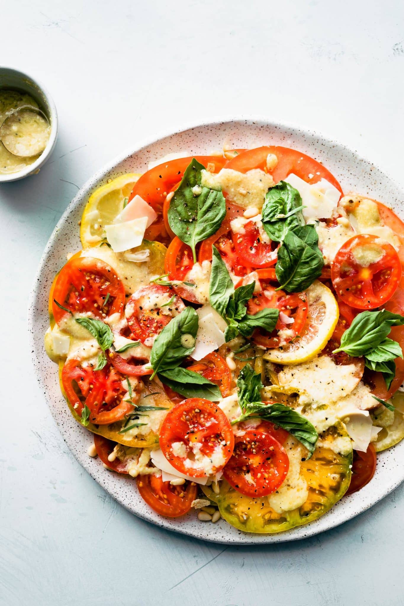 Caesar style tomato salad recipe topped with shaved Parmesan and fresh herbs