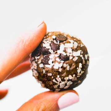 two fingers holding a coconut chocolate protein ball