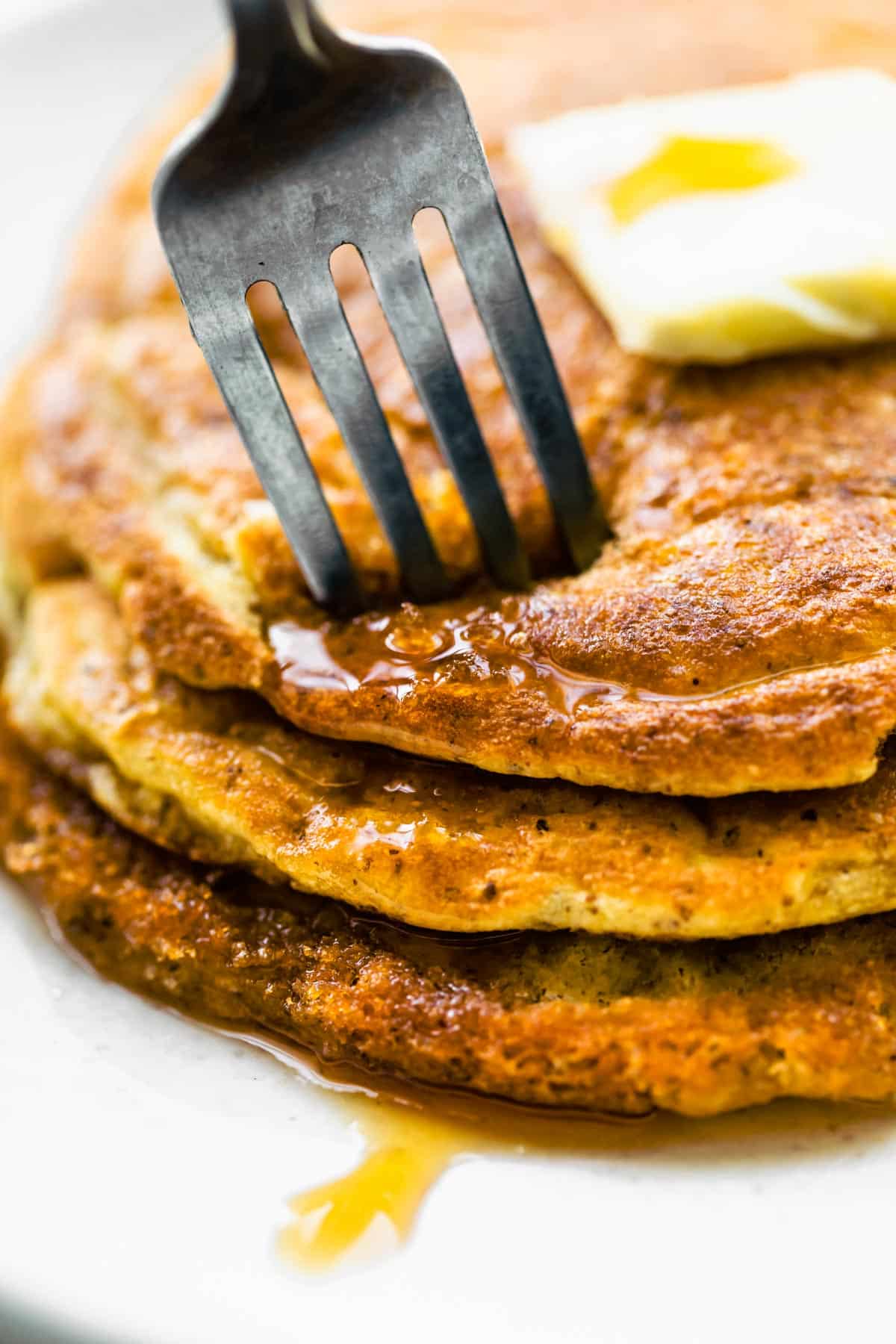 a fork stabbing into a stack of three coconut flour pancakes