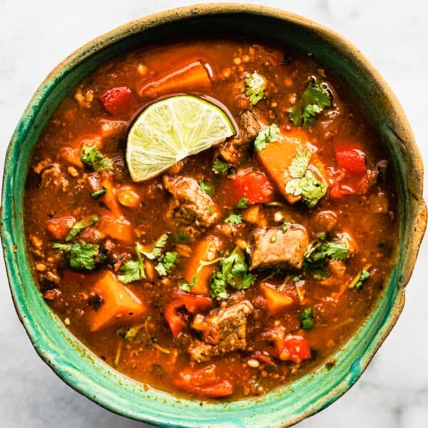 holding a bowl of gluten-free Mexican sweet potato beef stew (slow cooker recipe)