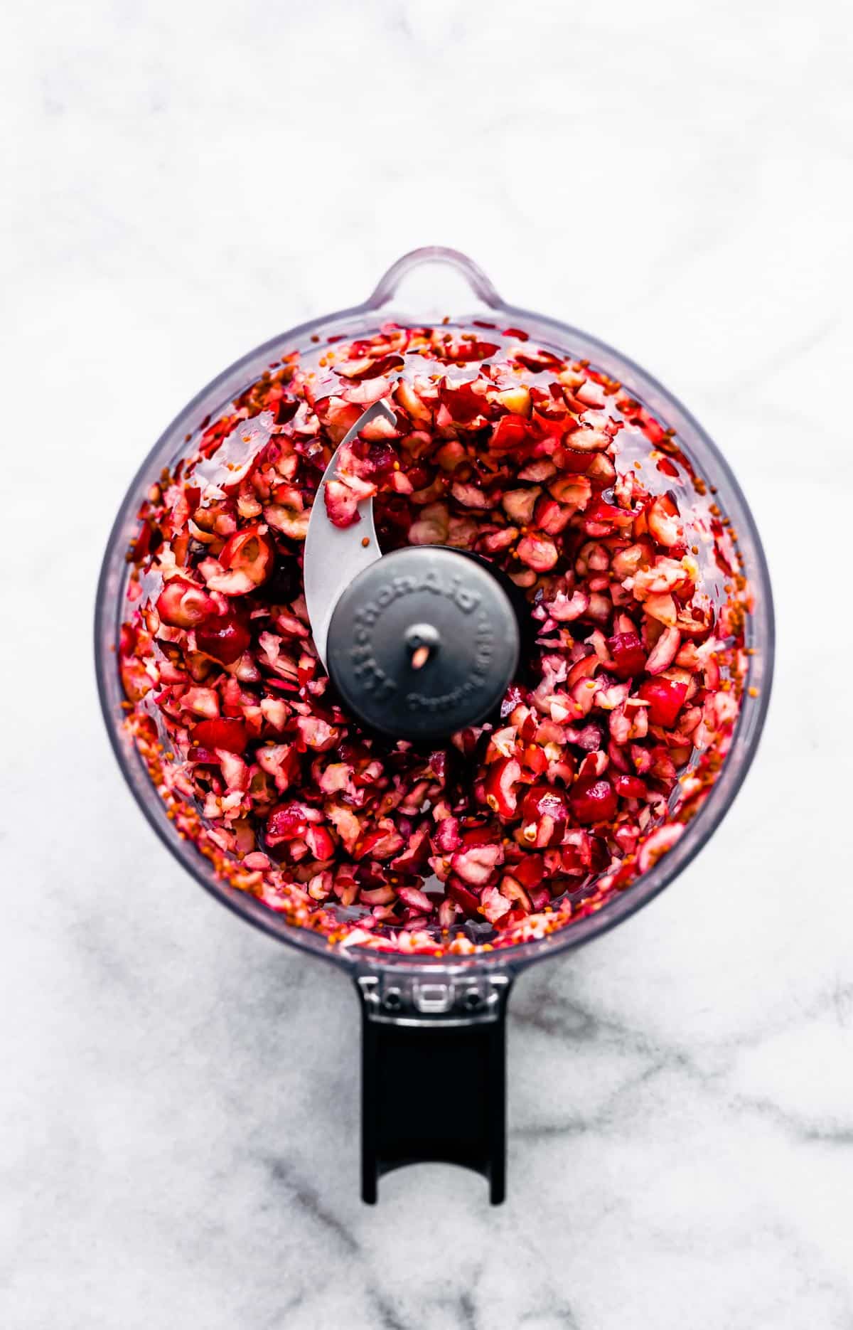 overhead image of pieces of fresh cranberries in a food processor