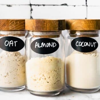 three glass jars full of gluten free flours including oat flour, almond flour, and coconut flour