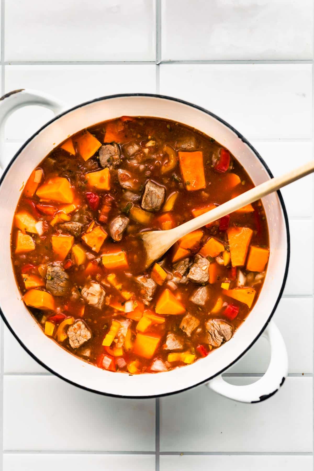 overhead image of a pot of Mexican sweet potato beef stew with a wooden spoon sticking out