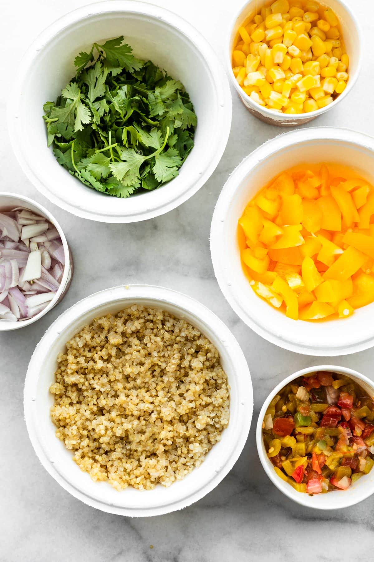 overhead image of bowls of quinoa, bell pepper, herbs, onions, and other ingredients to make a one skillet mexican quinoa recipe