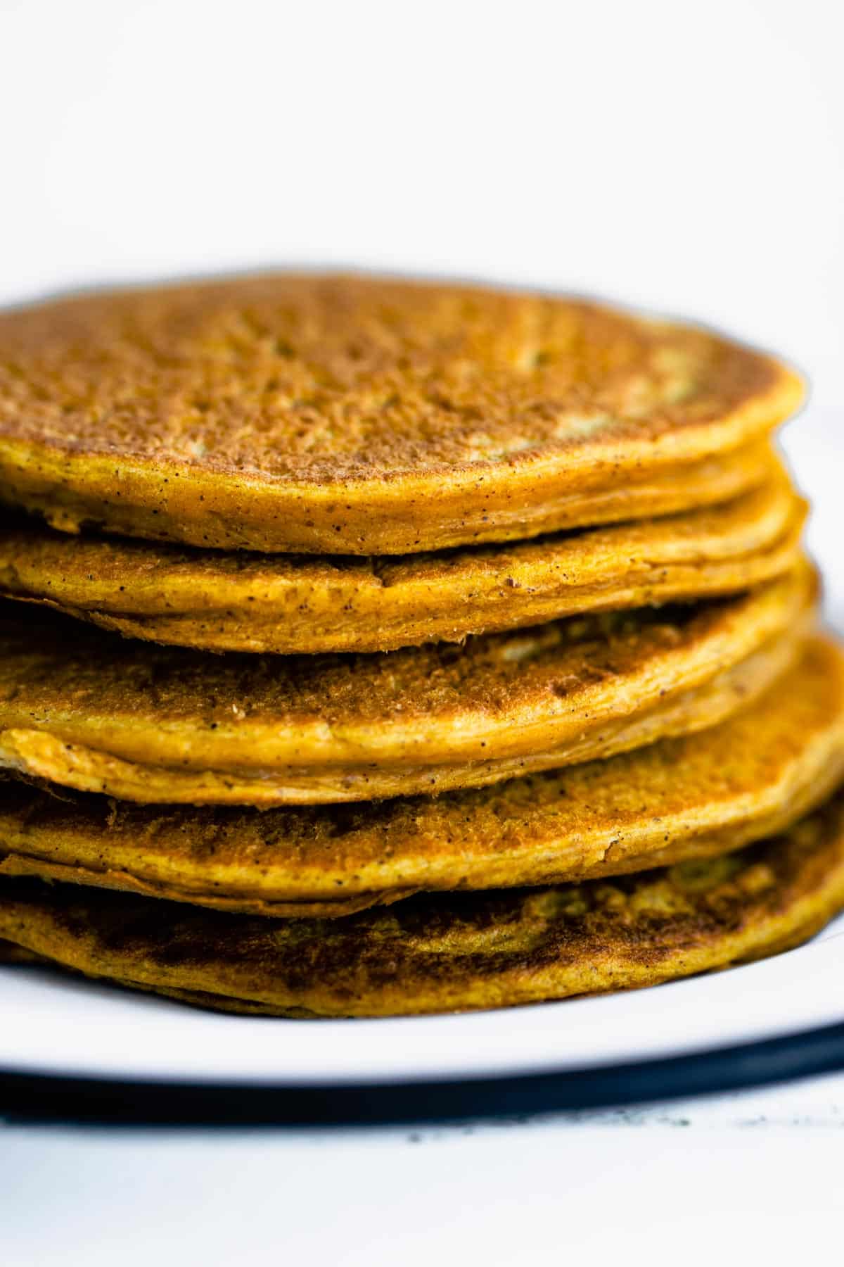 a stack of five vegan pumpkin pancakes on a white plate