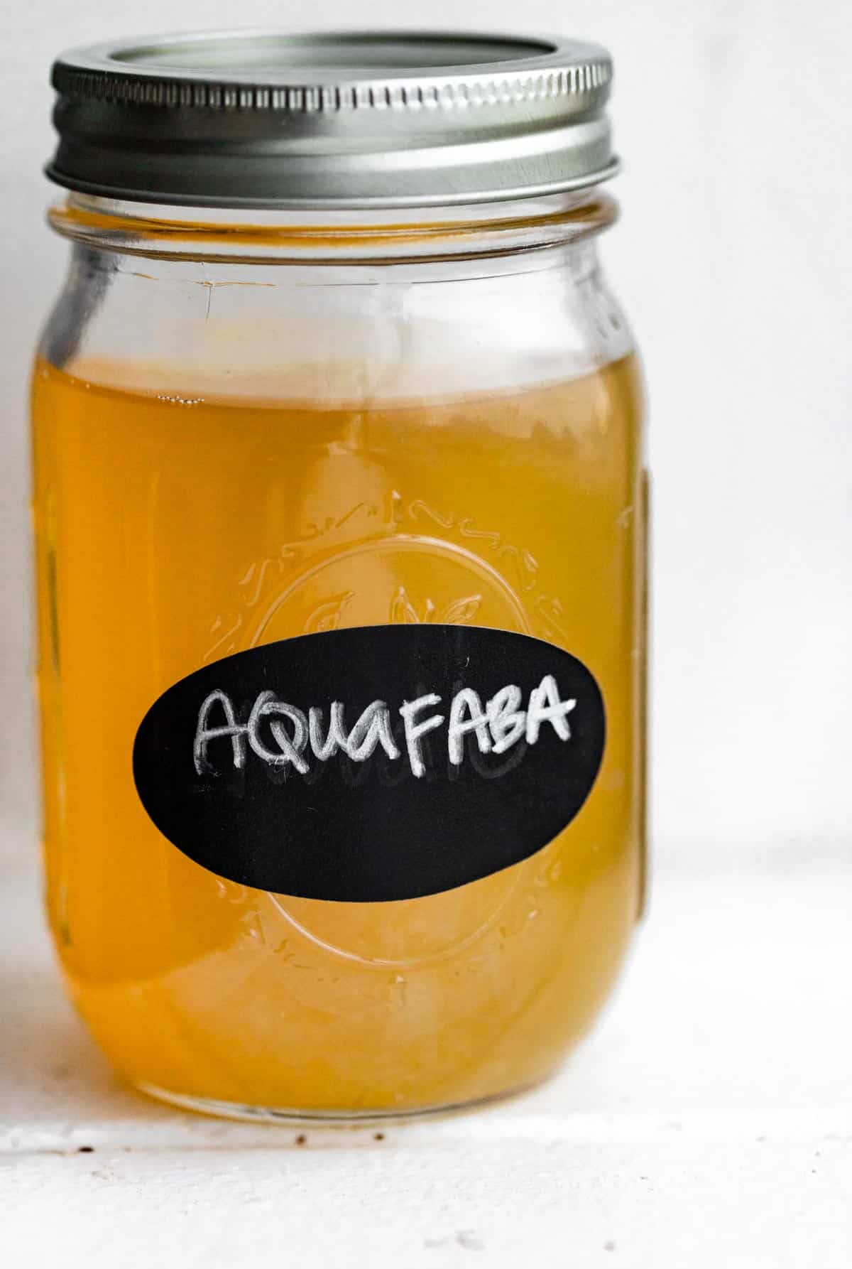 a mason jar full of liquid labeled aquafaba