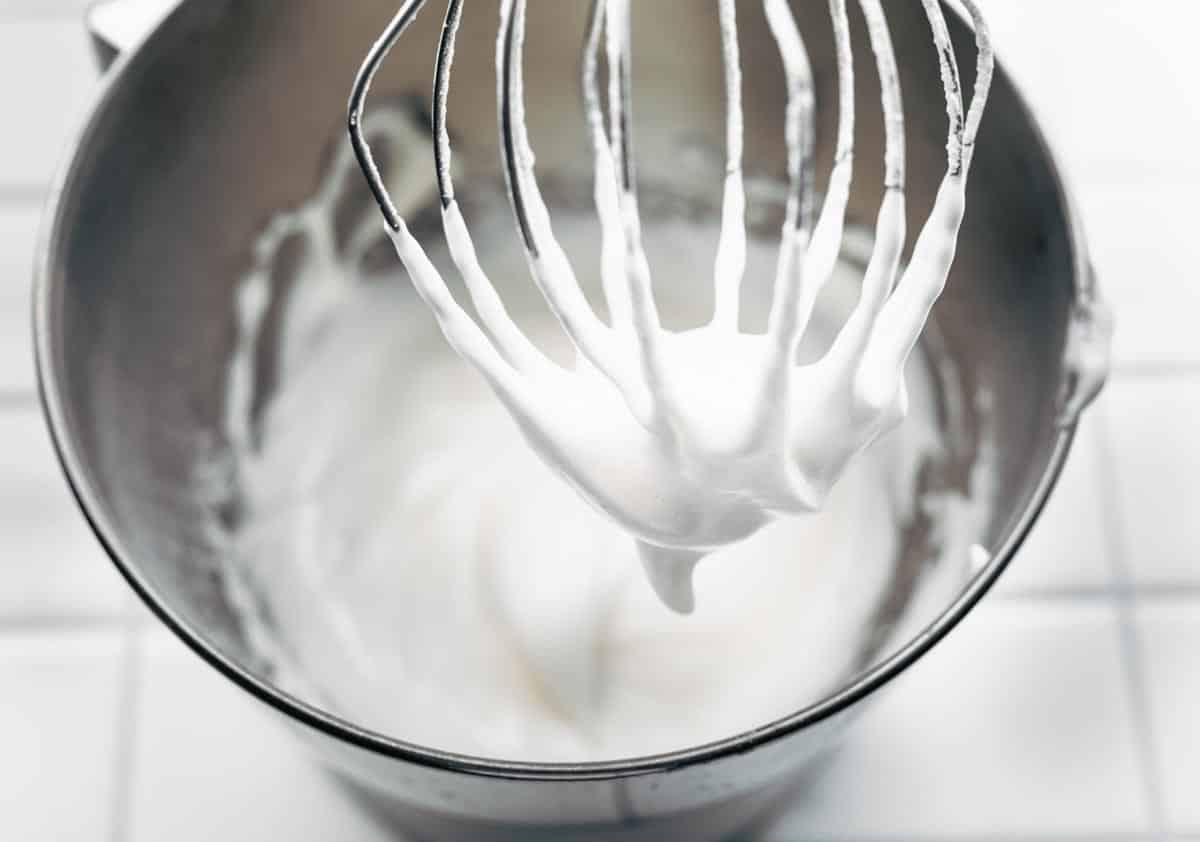 aquafaba whipped cream in a mixing bowl and on a whisk