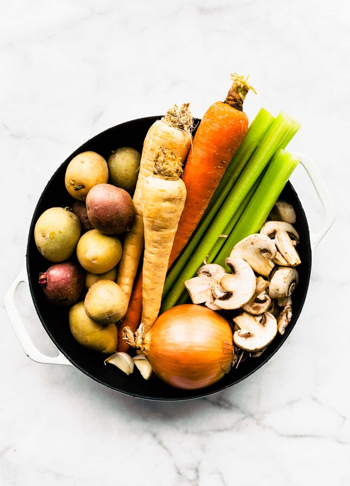Potatoes, carrots, onions, celery, and mushrooms in a bowl