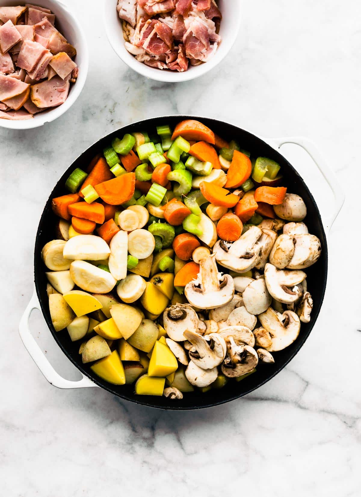 Chopped potatoes, carrots, celery, and mushrooms in a pot