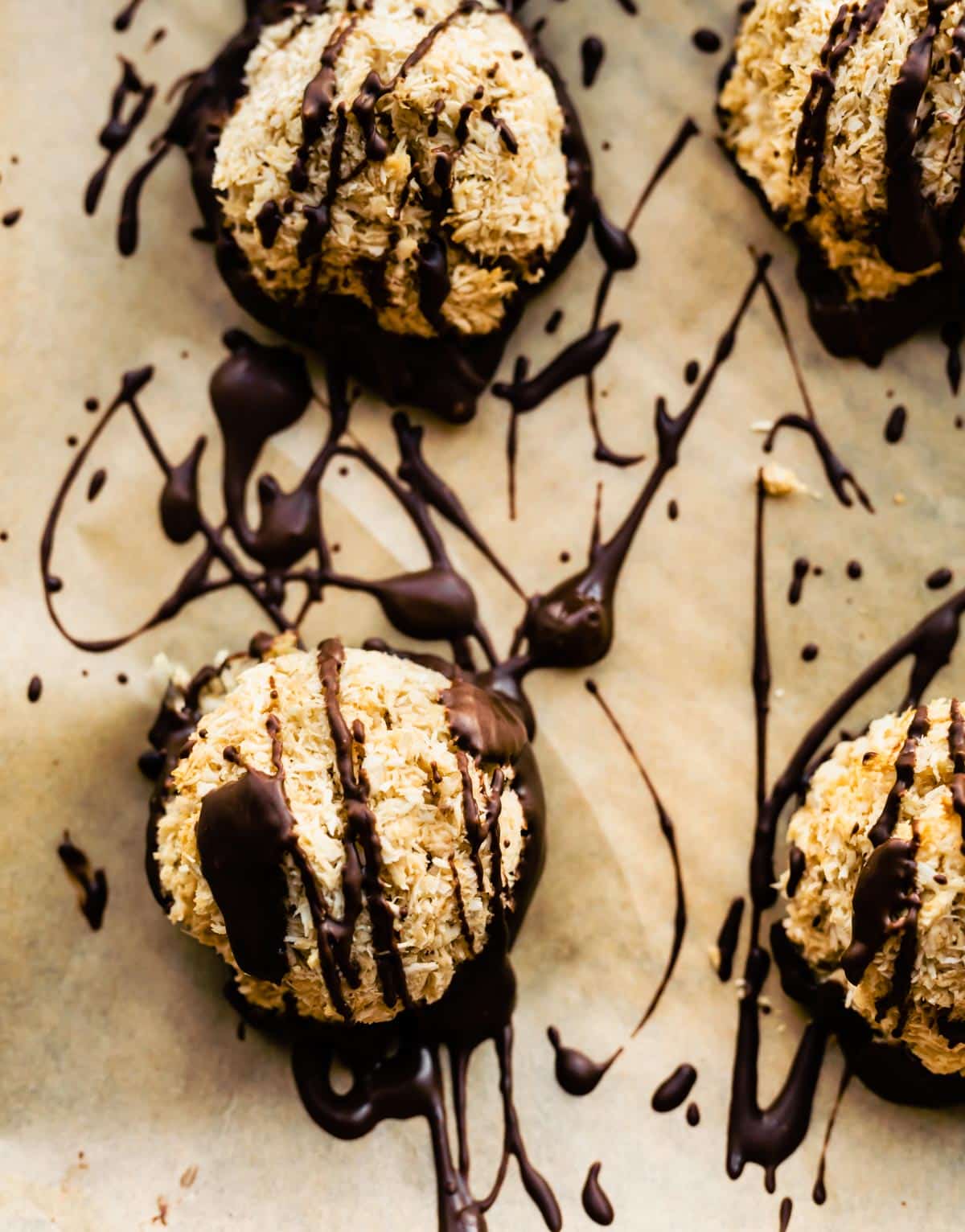 close up image of vegan gluten free mocha coconut macaroons drizzled with dark chocolate on parchment paper
