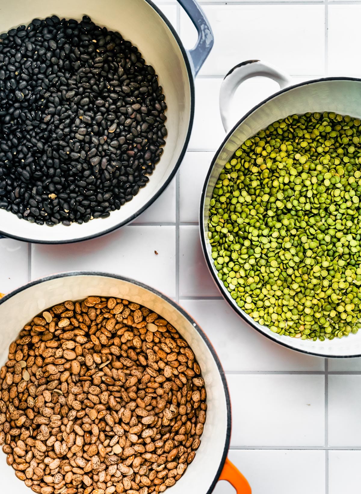 Overhead shot of Black Beans, Green Lentils, and Pinto Beans all in separate pots on counter top.