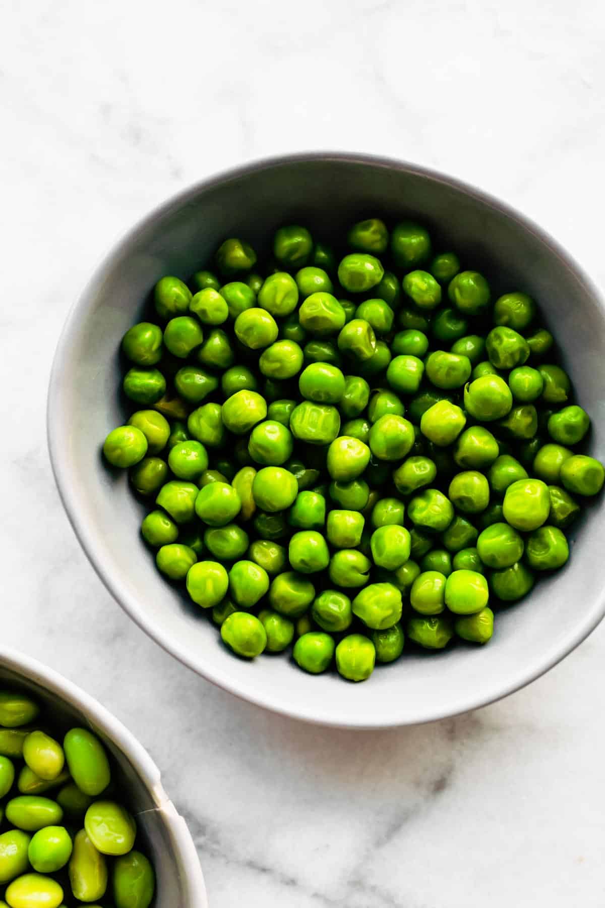 A bowl of green peas on a table.