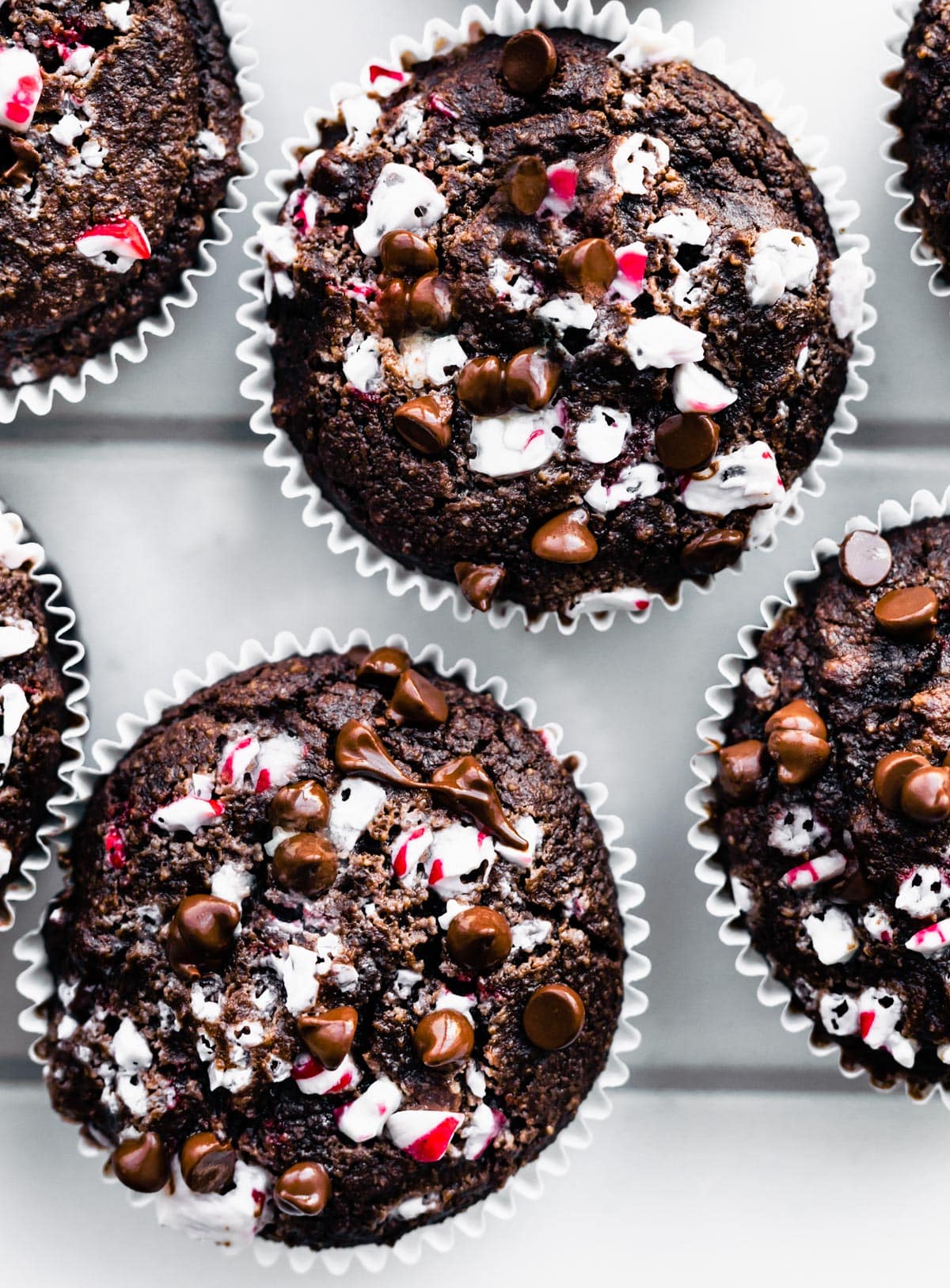 Overhead photo of pretty gluten free Peppermint Chocolate Muffins topped with mini chocolate chips and crushed peppermint candies.