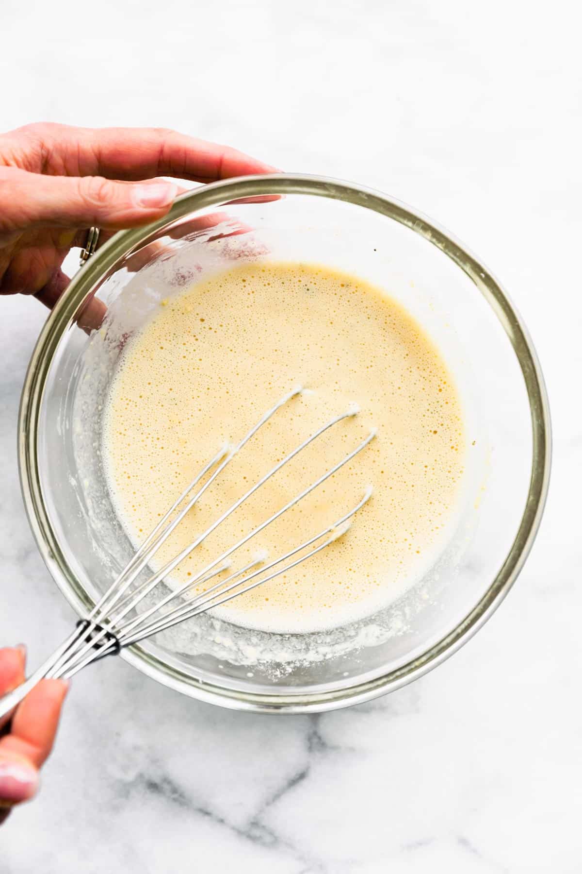 Socca batter being mixed by a whisk