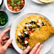 Hands folding up filled Savory Chickpea Pancake