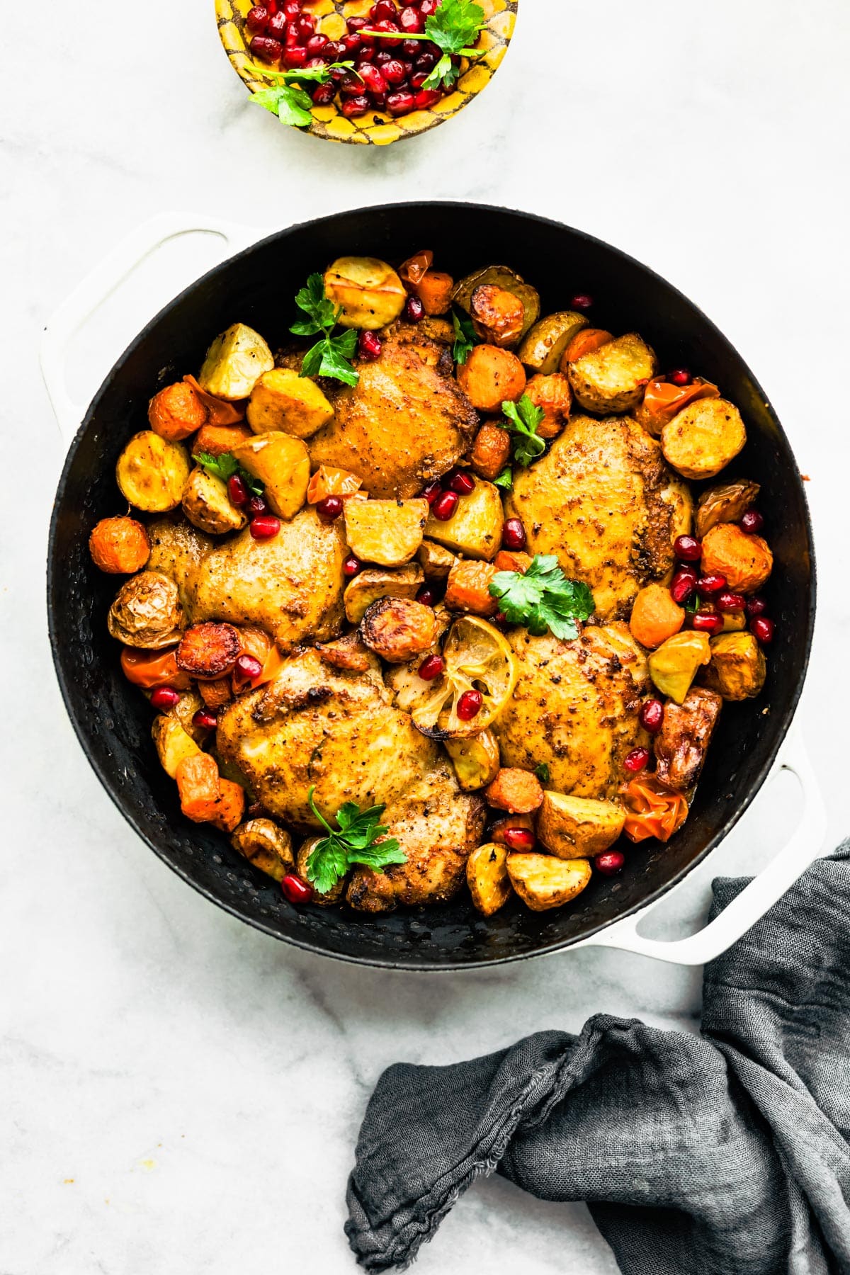 Overhead shot of Persian-Spiced Chicken and Potatoes in a pot with garnish on a countertop.