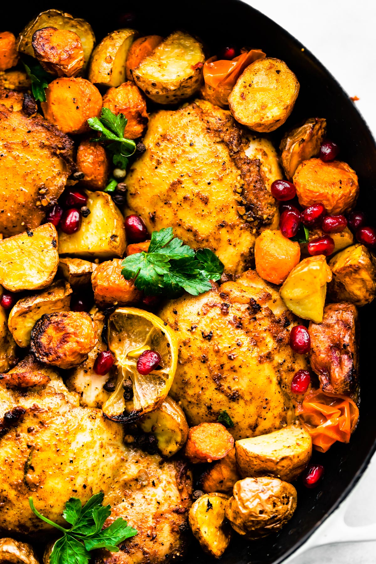 Close-up shot of Persian-Spiced Chicken and Potatoes  in a pan garnished with pomegranates 